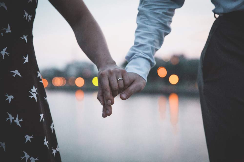 Close-up of a married couple holding hands.