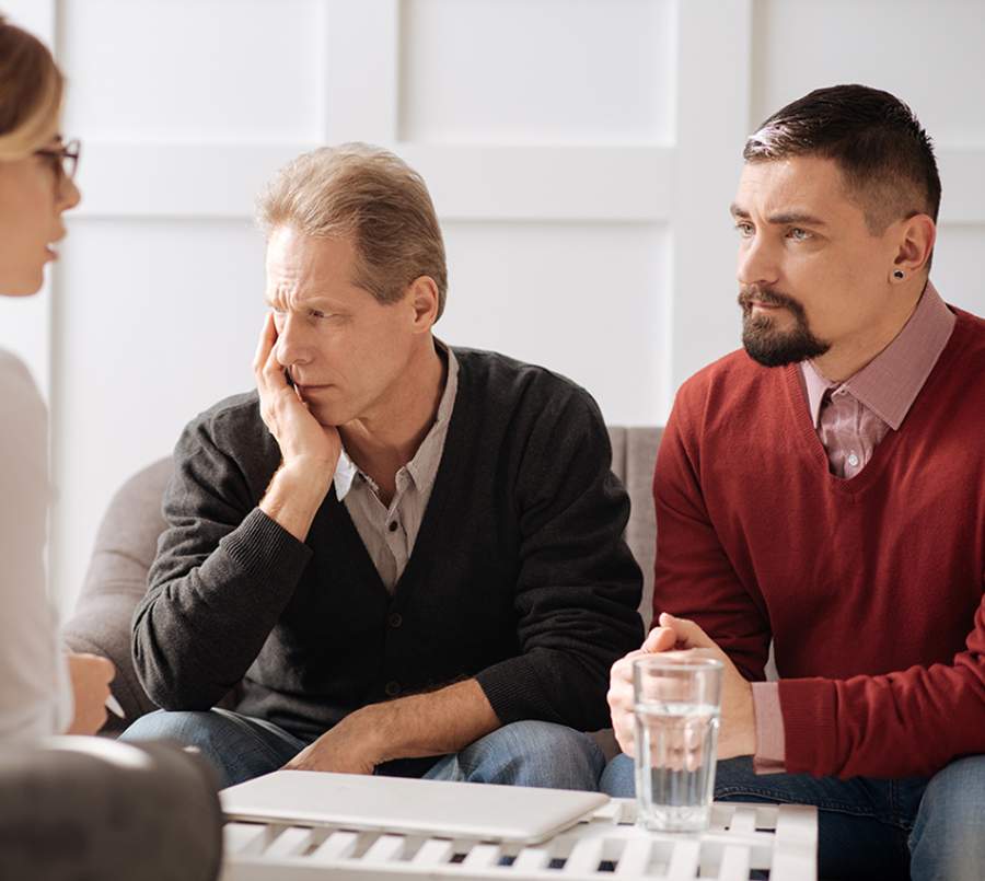 A couple sitting together during a therapy session, both appearing deep in thought and concern.